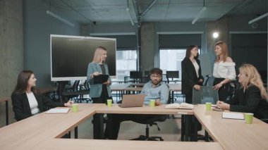 Meslektaşlar bir takım toplantısı sırasında modern bir ofis alanında proje planlarını tartışırlar