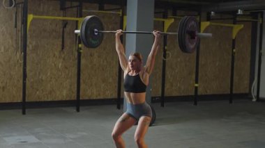 Güçlü atlet antrenman sırasında güç ve kuvvete odaklanarak spor salonunda halter kaldırıyor.