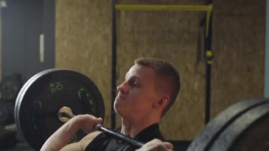 Spor salonunda antrenman yapan sporcu, akşam oturumunda güç ve kondisyon egzersizleri için ağırlık kaldırıyor.