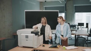 Yoğun bir iş gününde ofis ortamında bir yazıcının çalışma görevlerini tartışan iki kişi