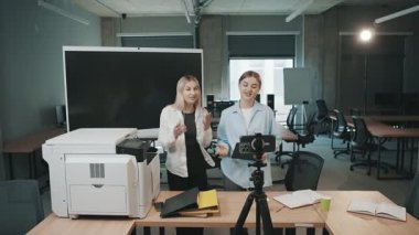 Ofiste bir yazıcı ve kamera kurulumuyla projeleri tartışan iki kadınla iş görüşmesi.