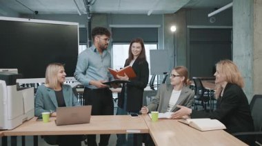 Modern ofis alanında yeni proje önerilerini tartışan bir grup profesyonelle iş toplantısı