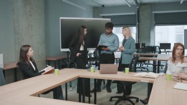 Proje ayrıntılarını incelerken modern ofis ortamında iş profesyonelleri arasında tartışma