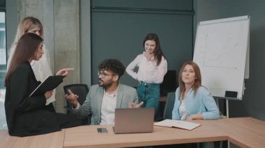 Ofis ortamında çizelgeler ve bir bilgisayar eşliğinde takım üyeleri arasındaki iş stratejileri hakkında tartışmalar