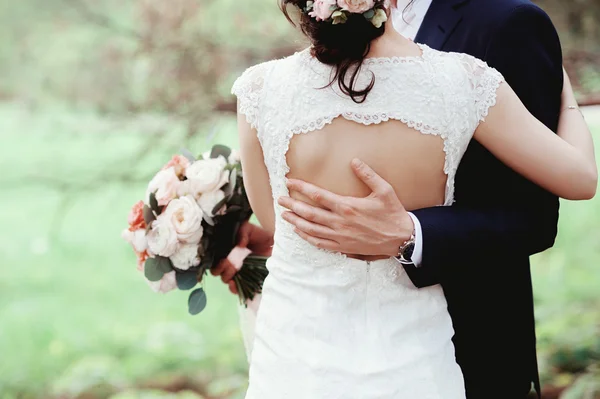 La mariée et le marié, bras dans le bras, au milieu de verdure naturelle. mains de jeunes mariés ensemble. Couple de mariage . — Photo