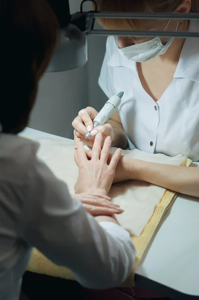 Técnico de uñas profesional lijando clavos con máquina — Foto de Stock