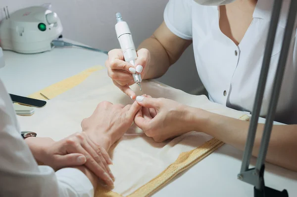 Profesional nail technician sanding nails with machine — Stock Photo, Image