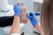Fußpfleger entfernt trockene Haut an der Fußsohle einer Frau