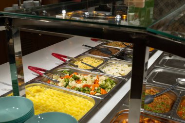Servis hattındaki servis tabakları, self-servis restoranı. Buharda pişmiş sebze, pirinç, karabuğday, patates. Copispace.