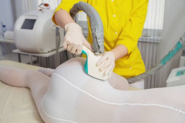 Beyaz takım elbiseli bir kadın spa salonunda selülit karşıtı masaj yaptırıyor. Klinikte LPG ve vücut şekillendirme tedavisi