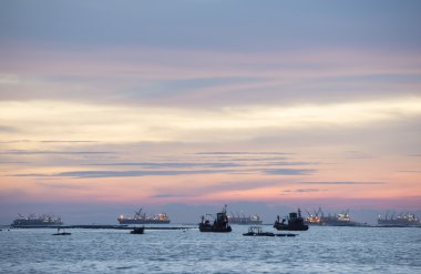 Alacakaranlık ve günbatımı balıkçı teknesi ve kargo ile denizde gemi