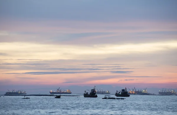 Crepúsculo e pôr do sol no mar com barco de pesca e navio de carga — Fotografia de Stock