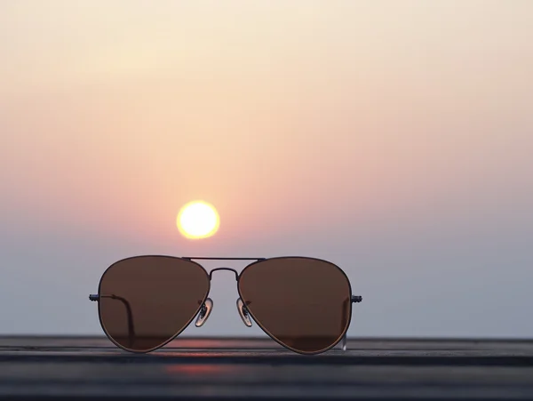 Closeup gözlük ile üzerinde duruldu ve gün batımı manzaralı bulanık — Stok fotoğraf