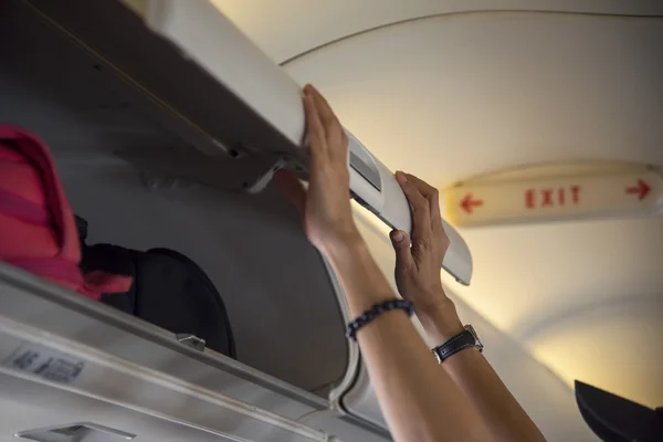 Mujer viajera abre casillero en el avión —  Fotos de Stock