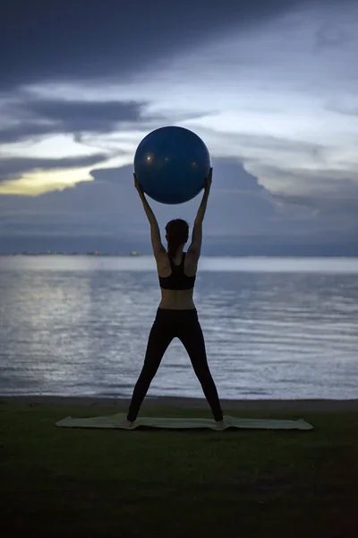剪影瑜伽球勇女子在海滩日落背景 — 图库照片