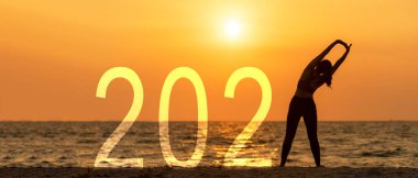 Yeni Yıl Kartın kutlu olsun 2021. Siluet yaşam tarzı kadın gün batımında deniz sahillerinde özgürce dinleniyor. Başlama başarısı 2021. Tatil Konsepti