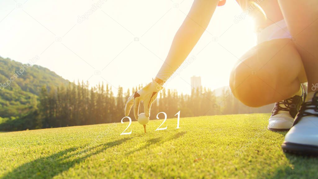 Golfer woman putting golf ball for Happy New Year 2021 on the green golf for new healthy.  copy space. Healthy and Holiday Concept.
