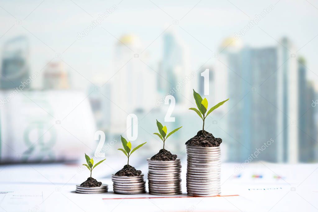 2021 New year on growing up money coin stack for investment.  Economic and business growth in 2021, planning financial report for investor real estate business, city background. 