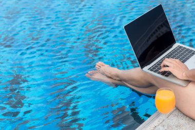 Yaklaş ve bacaklarını seç. Yaz zamanı ve tatiller. Kadın yaşam tarzı rahatlama ve yüzme havuzunda dizüstü bilgisayar kullanma, yaz günü oteldeki plaj tatil köyünde. Yaz Konsepti