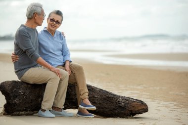 Asya yaşam tarzı yaşlı çiftler romantik aşıklar kucaklaşır ve kumsalda mutlu bir şekilde romantik romantik bir şekilde oturur ve dinlenirler. Eski aile turizmi tatiller ve yaz tatilleri sonrasında tatil ve etkinlik.