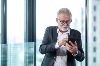 Kıdemli işadamı akıllı telefon iletişimi kurarak iş yapıyor. İnsanlar yatırım için akıllı telefondan veri borsasından emekli oluyor. Şehir geçmişi. İş ve Teknoloji Konsepti.