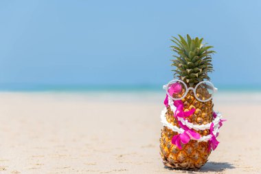 Partide yaz mevsimi. Kum sahilinde güneş gözlüğü içinde hippi Pineapple Fashion güzel mavi gökyüzü arkaplanı. Tropikal stil için yaratıcı sanat meyveleri. Moda Yaz Tatili Konsepti
