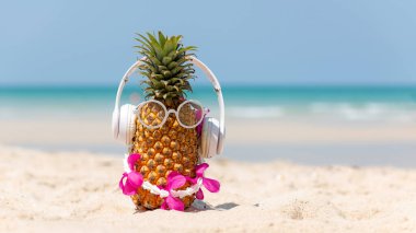 Partide yaz mevsimi. Güneş gözlüklü hippi Pineapple Fashion ve kumsalda güzel mavi gökyüzü arka planında müzik dinlemek. Tropikal stil için yaratıcı sanat meyveleri. Moda Yaz Tatili Konsepti