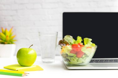Ofiste çalışmak sağlıklı bir aperatif. Diyet sağlık planı için suyla birlikte yeşil elma ve taze salata. Dizüstü bilgisayarlı, beyaz elbiseli. Sağlıklı Yaşam Tarzı Konsepti
