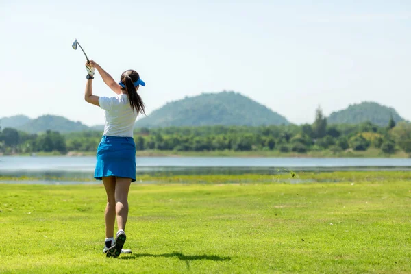 Golfer sport course golf ball fairway. People lifestyle woman playing game golf and hitting go on green grass river and mountain background.  Asia female player game shot in summer.  Healthy and Sport