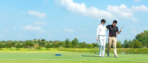 Grup golfü. Profesyonel Golfçü Asyalı adam yeşil topa vurduktan sonra dostluk için sarılıyor. Hobi tatilde dinlenir ve arkadaşlarla tatile çıkar. Pankart için boşluk kopyala