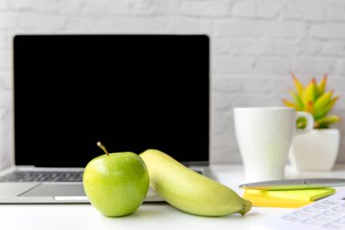 Ofiste çalışmak sağlıklı bir aperatif. Diyet sağlık planlaması için taze suyla yeşil elma ve muz, dizüstü bilgisayarın çalışma geçmişi. Sağlıklı Yaşam Tarzı Konsepti