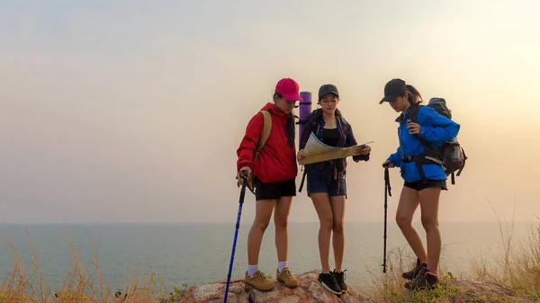 团体亚洲朋友带着背包历险旅行的人拿着地图去寻找方向 在靠近大海的高山上散步 户外日落 到目的地度假 享受休闲教育 旅行和生活方式概念 — 图库照片