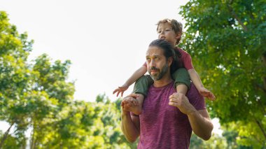 Mutlu Aile. Babası onu mutlu bir şekilde taşırken ve bahçe parkında eğlenirken mutlu küçük çocuk ellerini uzatıyor. Baba ve oğul yaz günü dışarıda dinlenir ve dinlenir. Aile ve Yaşam Tarzı Kavramı
