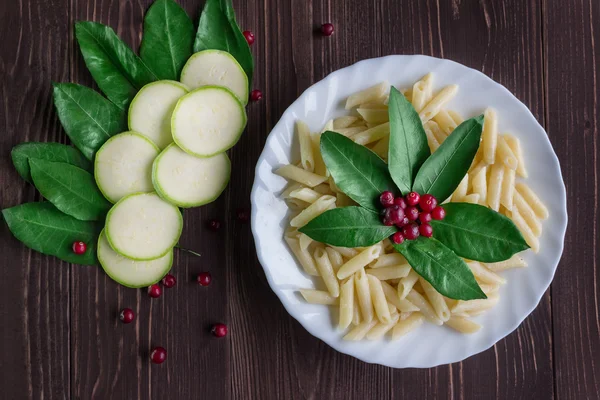 Bir porsiyon makarna ile dekore edilmiş yaprakları ve meyveleri