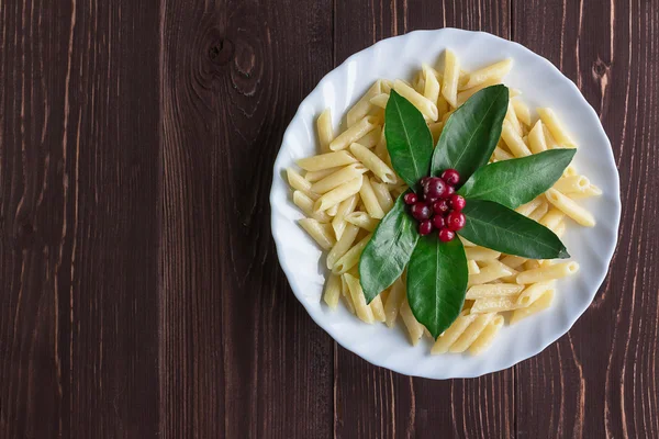 Bir porsiyon makarna ile dekore edilmiş yaprakları ve meyveleri