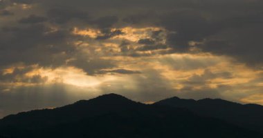 Yağmur ve fırtına bulutlarıyla kaplı kasvetli bir gökyüzünde, bulutların arasındaki ışık demetlerinin zamanlanmış görüntüleri..