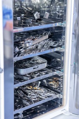Steril işlem dolabı paslanmaz cerrahi aletler ve tepsilerle dolu, sağlık eğitimi, güvenlik malzemeleri ve tıbbi kataloglar için ideal.