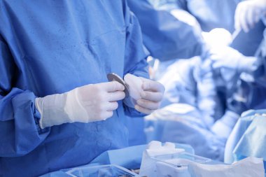 Eldivenli klinisyen modern bir ameliyathanede steril bir alanda diz protezi için femoral bileşen ve polietilen tibiyal hazırlıyor..