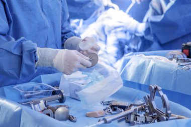 Cerrah diz implantı ve steril mavi perdelere modern ameliyathane çalışma akışını ve ekipmanlarını gösteren eklem ameliyatını hazırlıyor..