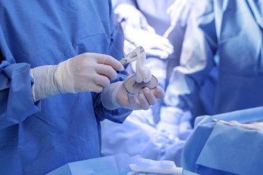 Eldiven cerrahı modern eklem ameliyatı sırasında steril bir alandaki tibiyal bileşene kemik çimentosu uygular..