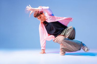 Hip hop dansçısı düşük açılı ayak hareketleri yapıyor ve gençlik reklamları, posterleri ve sosyal kampanyaları için geniş bir kopya alanı olan neon ışıklı bir stüdyoda donuyor..