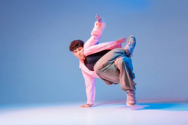 Hip hop dansçısı renkli stüdyo ışıklarında tek eliyle donarak, gençlik reklamları, müzik tanıtımları, posterler ve şehir kültür kampanyaları için ideal bir performans sergiliyor..