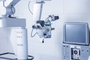 Temiz bir klinikteki monitör ve konsolla mikroskop ameliyata hazır.
