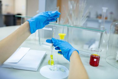 Eldivenli ellerin modern bir laboratuvarda şırınga ve beher kullanarak yakın plan çekimleri, kimya, ilaç, AR-GE, tanı ve sağlık hizmetleri içeriği için ideal