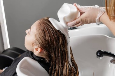 Eldivenli stilist tarağa bağlı ıslak iplikleri buduyor, ucu kesilirken temiz bir çizgi oluşturuyor, profesyonel bir kuaför saç kesimi tekniği..