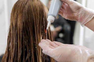 Eldivenli stilist tarağa bağlı ıslak iplikleri buduyor, ucu kesilirken temiz bir çizgi oluşturuyor, profesyonel bir kuaför saç kesimi tekniği..