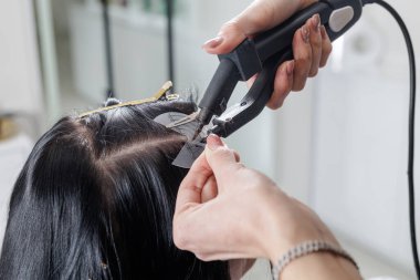 Eldivenli stilist tarağa bağlı ıslak iplikleri buduyor, ucu kesilirken temiz bir çizgi oluşturuyor, profesyonel bir kuaför saç kesimi tekniği..