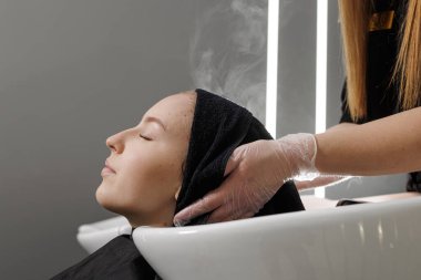 Eldivenli stilist tarağa bağlı ıslak iplikleri buduyor, ucu kesilirken temiz bir çizgi oluşturuyor, profesyonel bir kuaför saç kesimi tekniği..