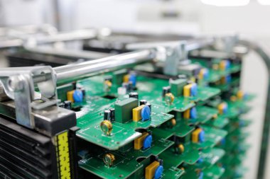 Modern otomatikleştirilmiş elektronik imalat tesisinde rafta duran birleştirilmiş yeşil baskılı devre kartlarının yakın görüntüsü