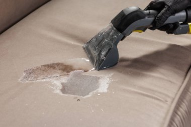 Derin temizlik sırasında döşeme yastığından sıvı dökülürken vakum hortumunun yakın görüntüsü